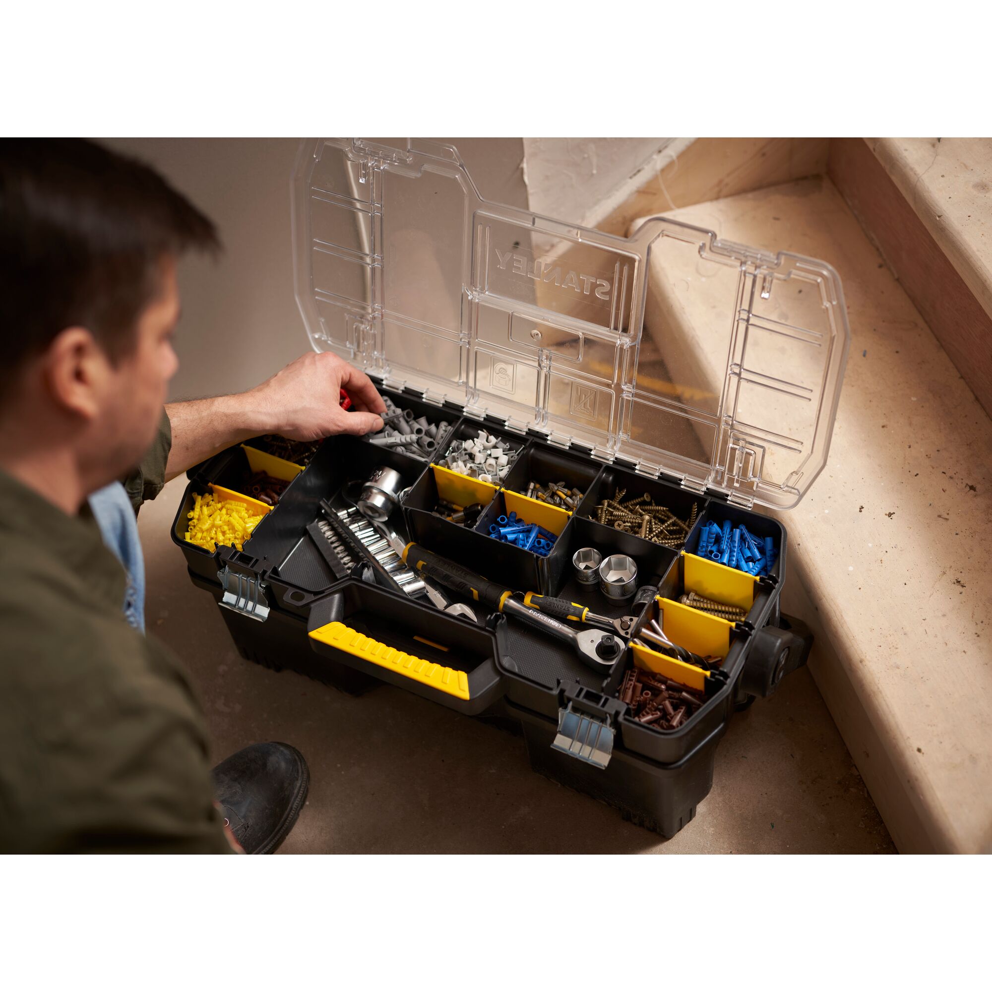 STANLEY 1-97-514 organizer box with clear lid, yellow handle, filled with tools and fasteners, side view.