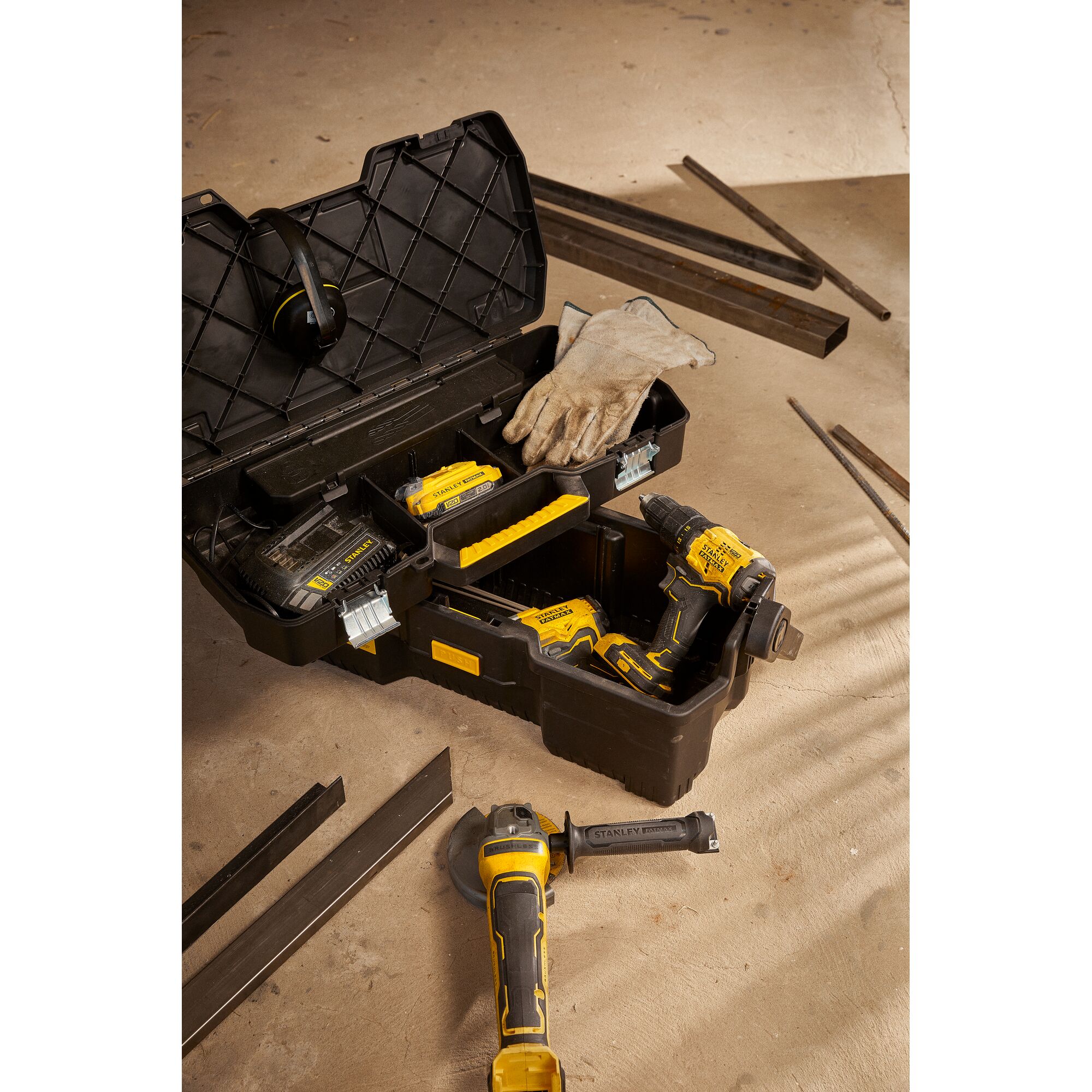 STANLEY SB202 black tool box with yellow handle, gloves, drill, grinder, and accessories, top-down angle.