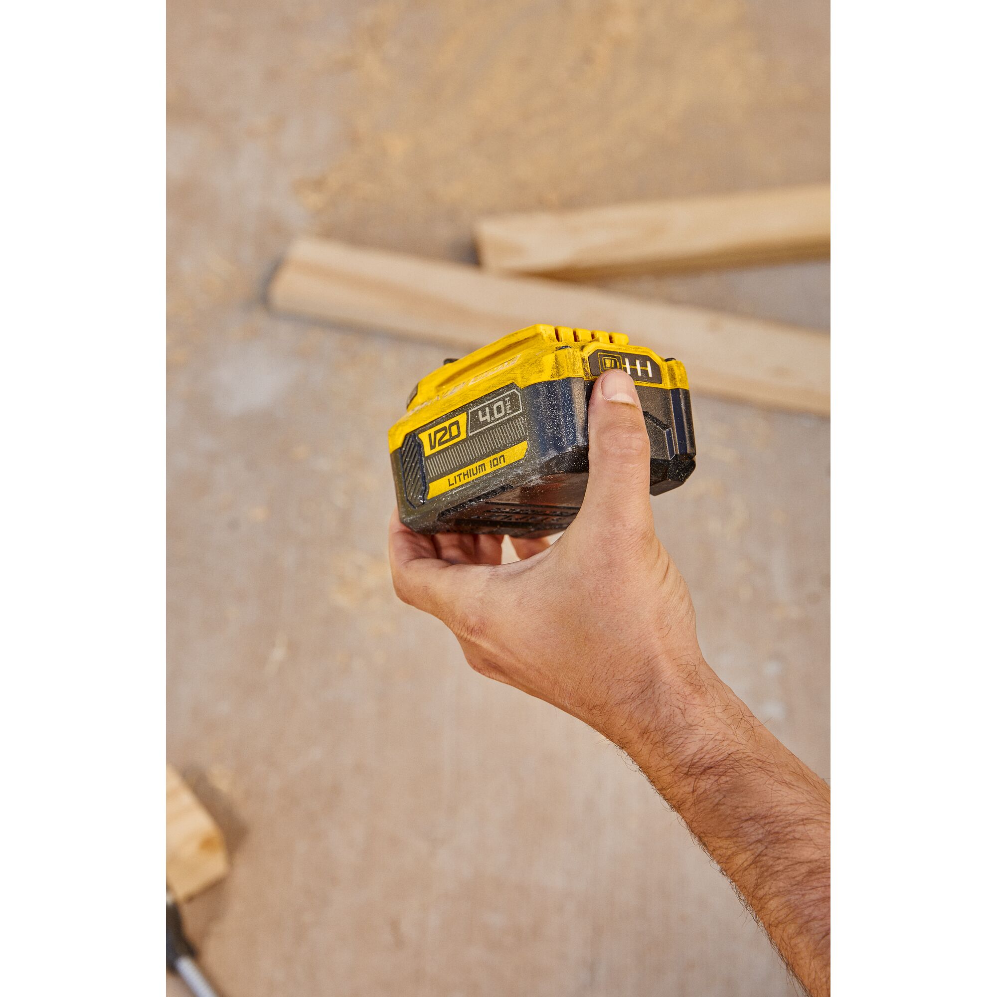 Photo of STANLEY SB204-KR V20 lithium-ion battery held in hand, construction wood background.