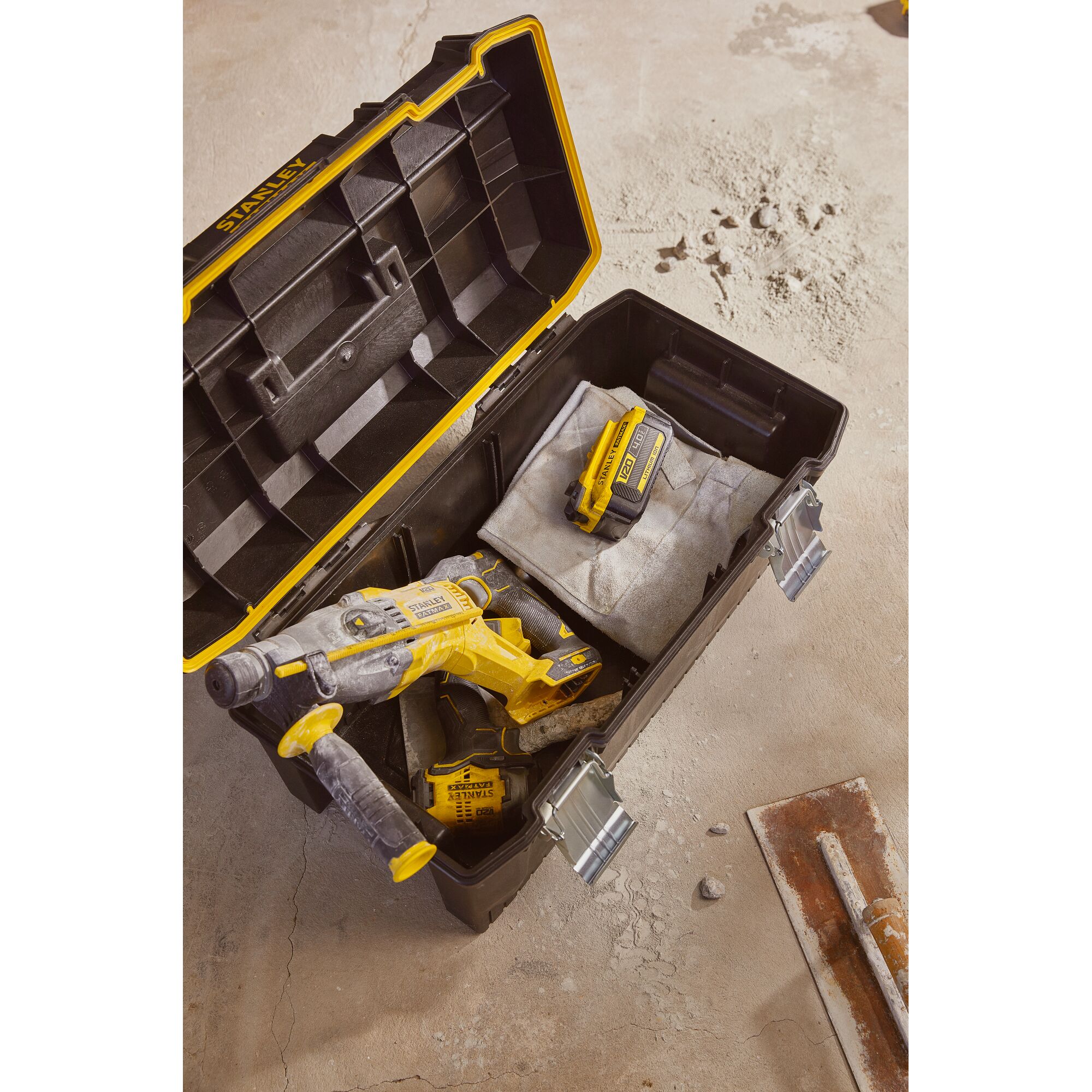 Stanley SB204-KR tool box with yellow power drill and battery, photographed from above on a concrete surface.