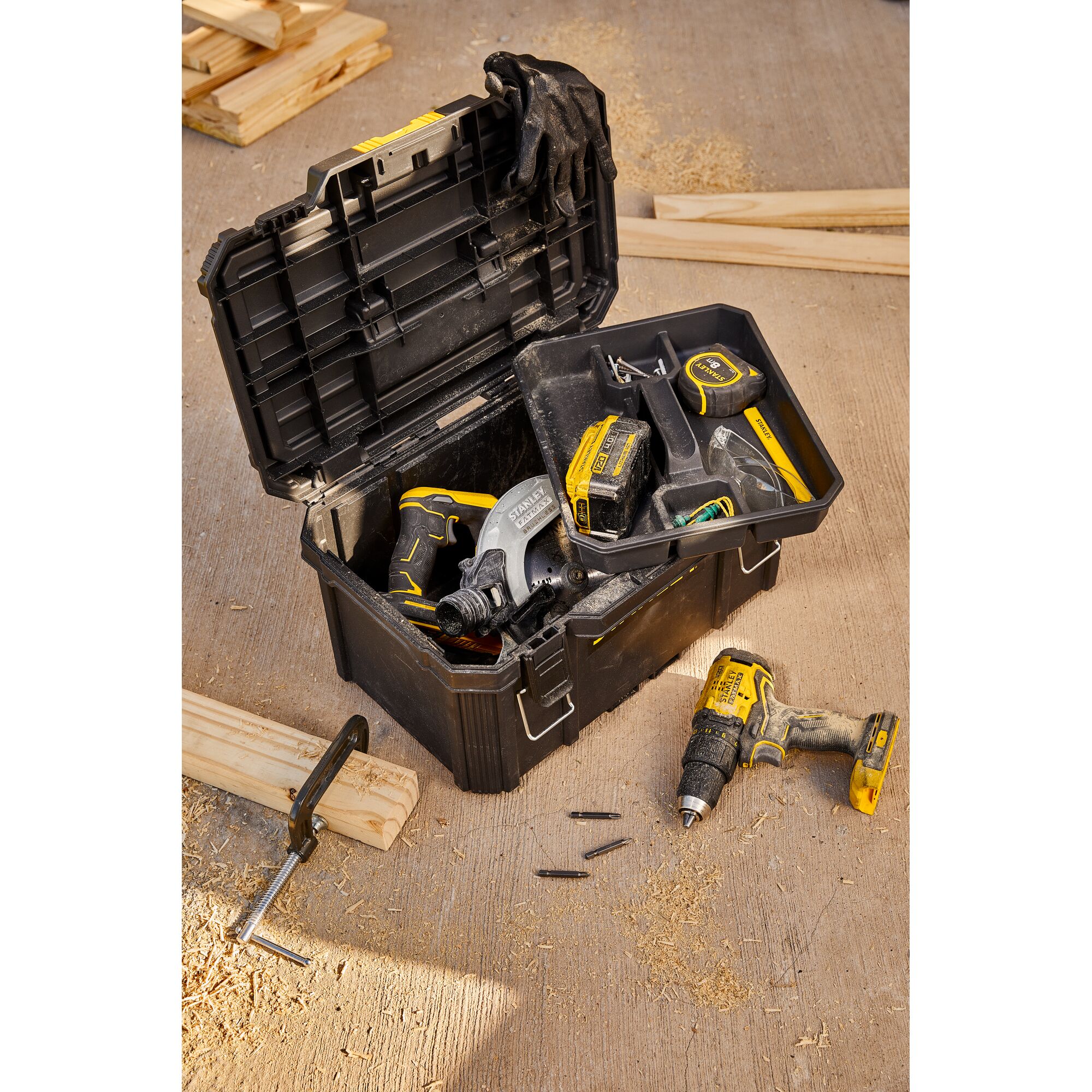 STANLEY SB204-KR black toolbox with tools including drill and tape measure on workshop floor.