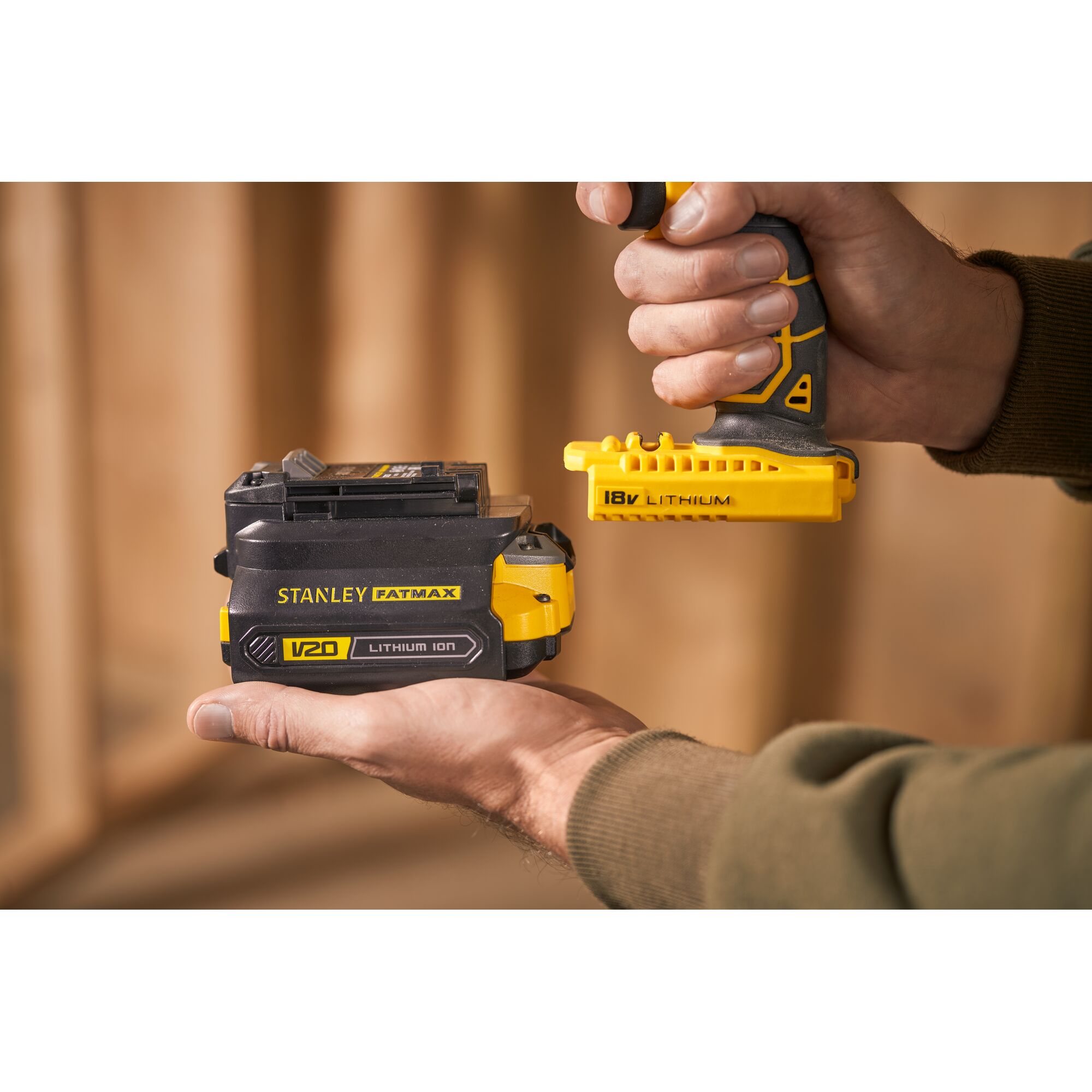 Stanley SBA100 V20 lithium ion battery in hand, close-up side angle, yellow and black casing.