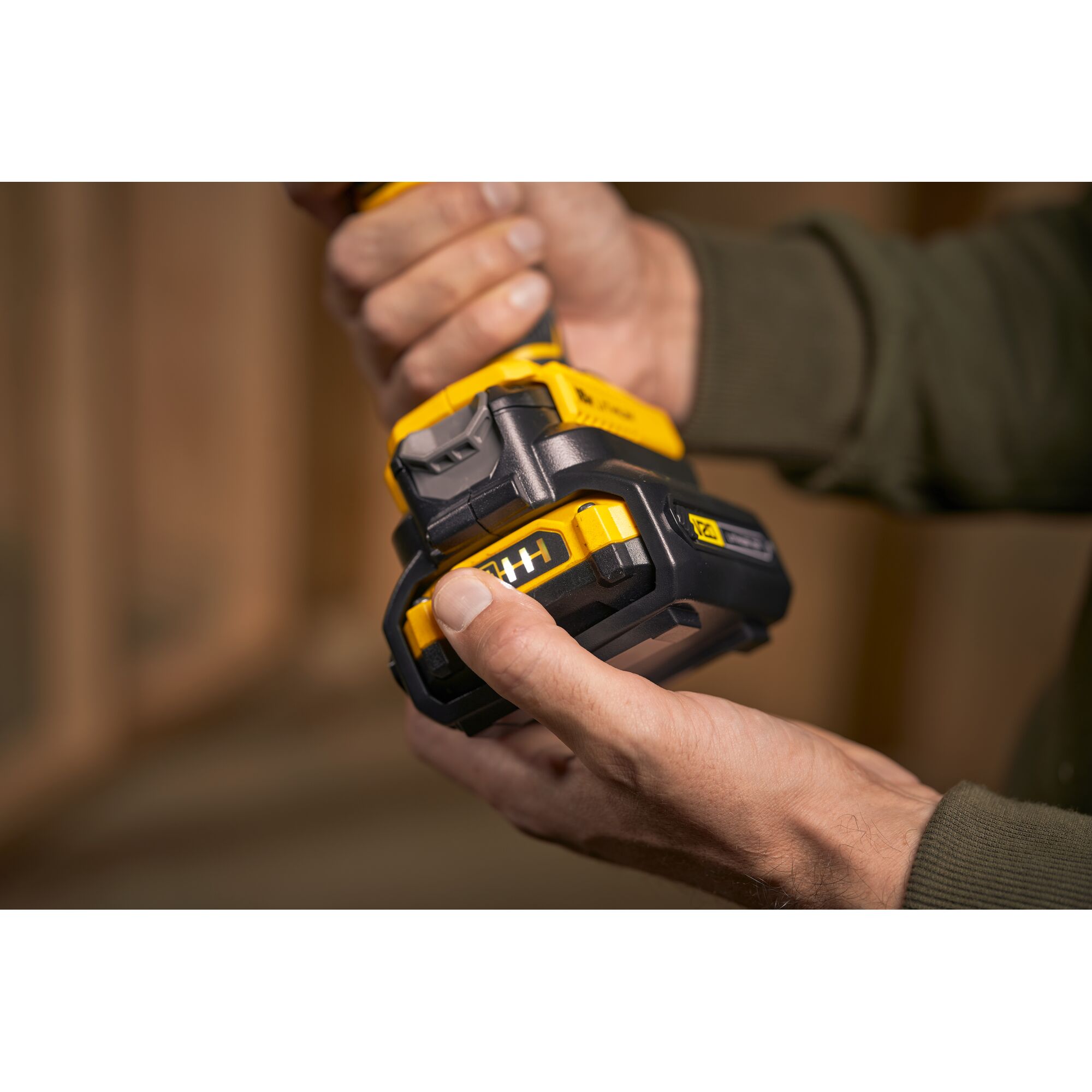 Photo of STANLEY SBA100 cordless tool battery in hand, close-up view, showing yellow and black design.