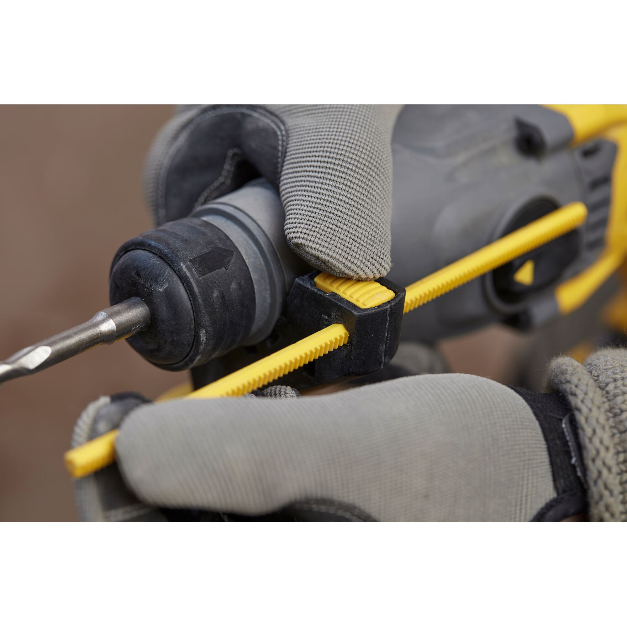 STANLEY SBH900M2K-B3 hammer drill close-up with gloved hands adjusting yellow depth gauge.