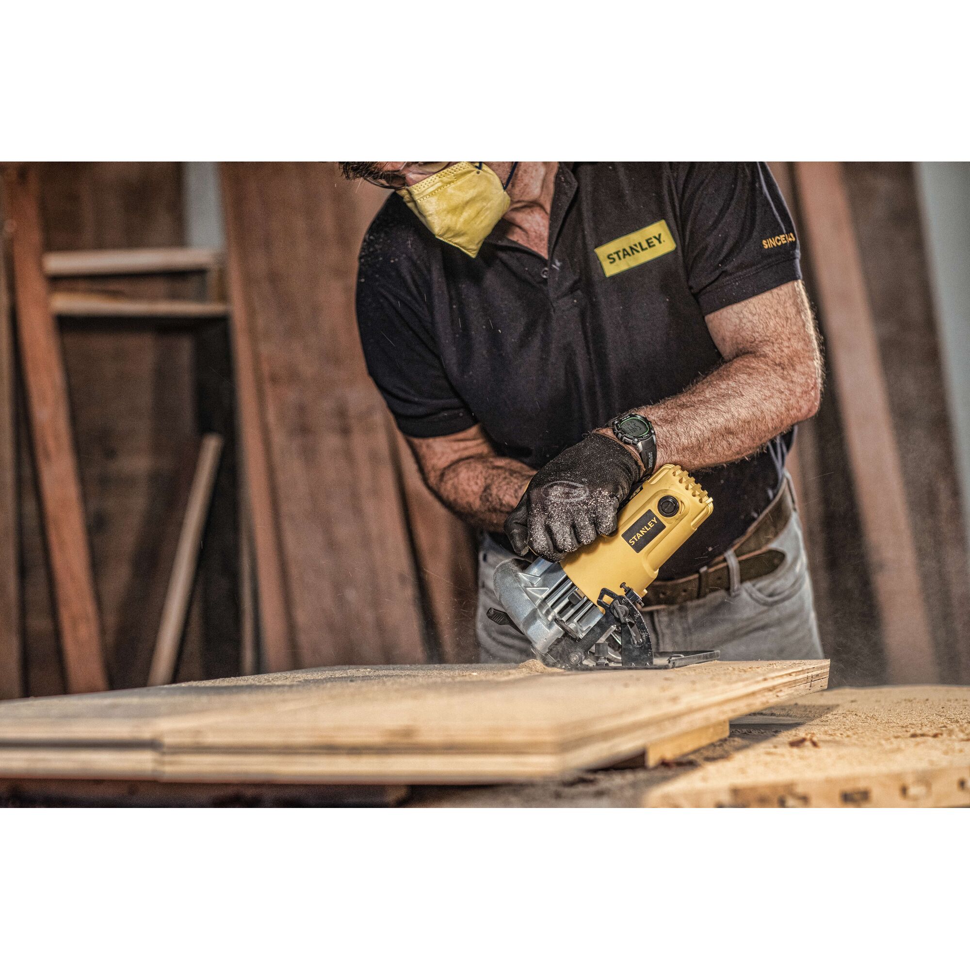 STANLEY SC16 circular saw cutting wood, photography of user wearing gloves and mask in workshop.