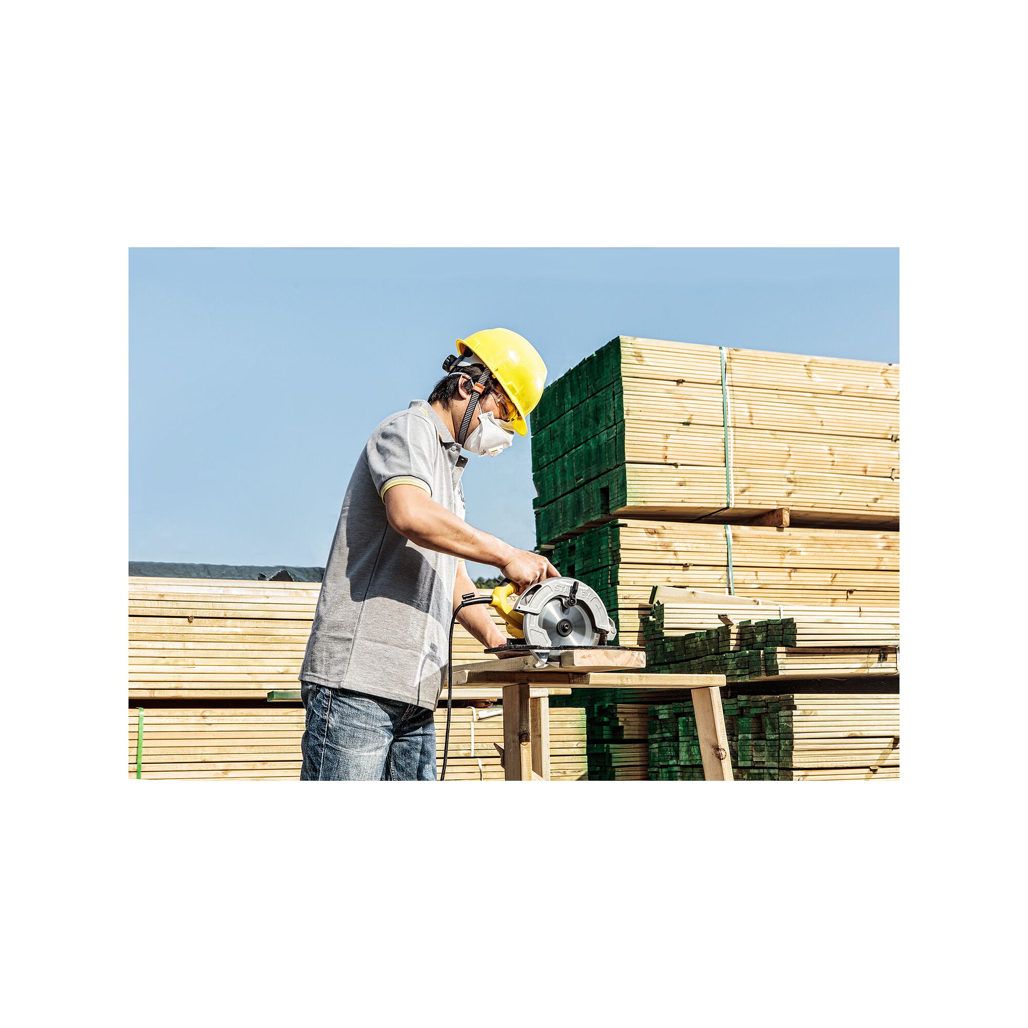 Photo of worker using STANLEY SC16 circular saw to cut wood on site, with lumber stacks in the background.
