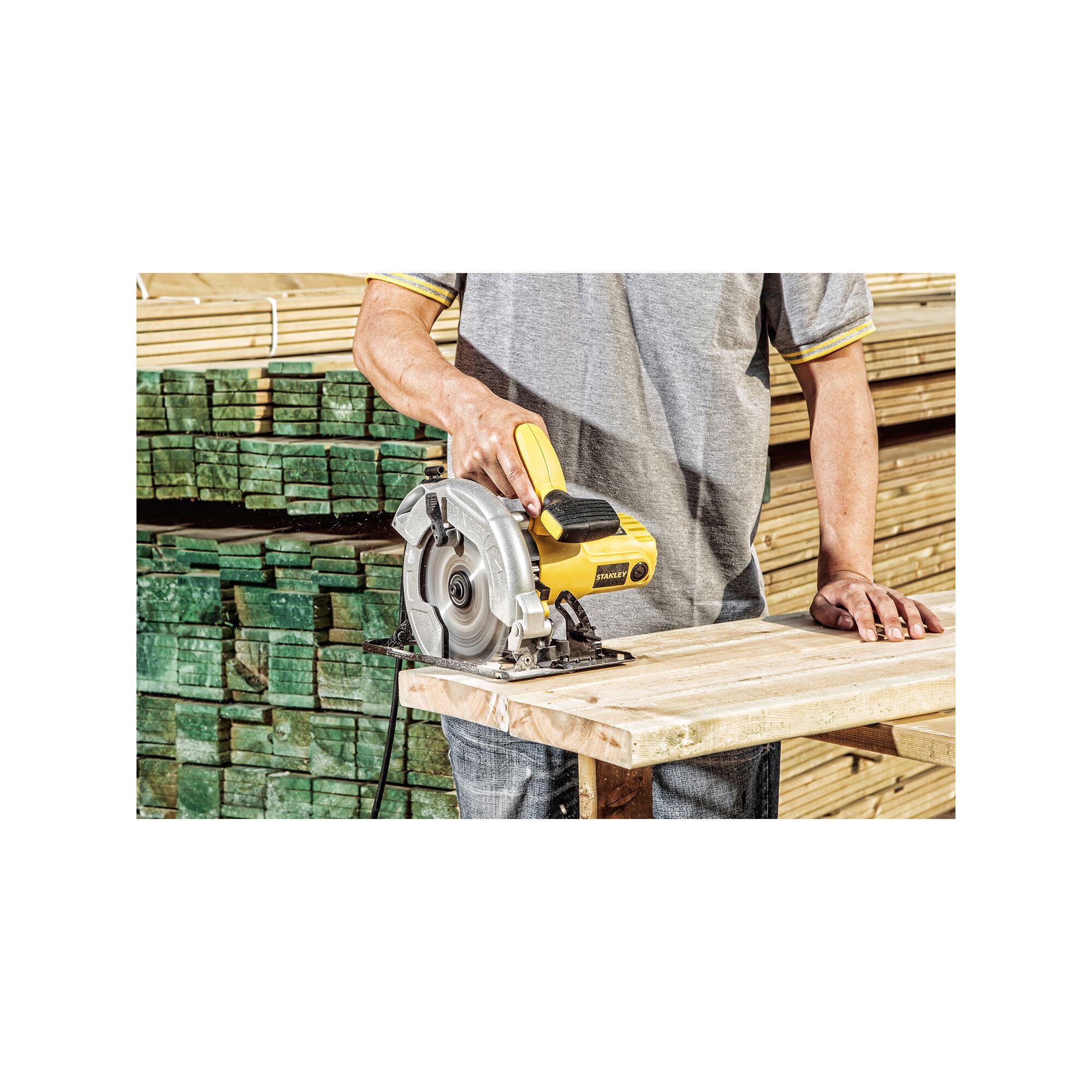 Photo of STANLEY SC16 circular saw cutting wood, operated by person wearing grey shirt, lumber stacked in background.