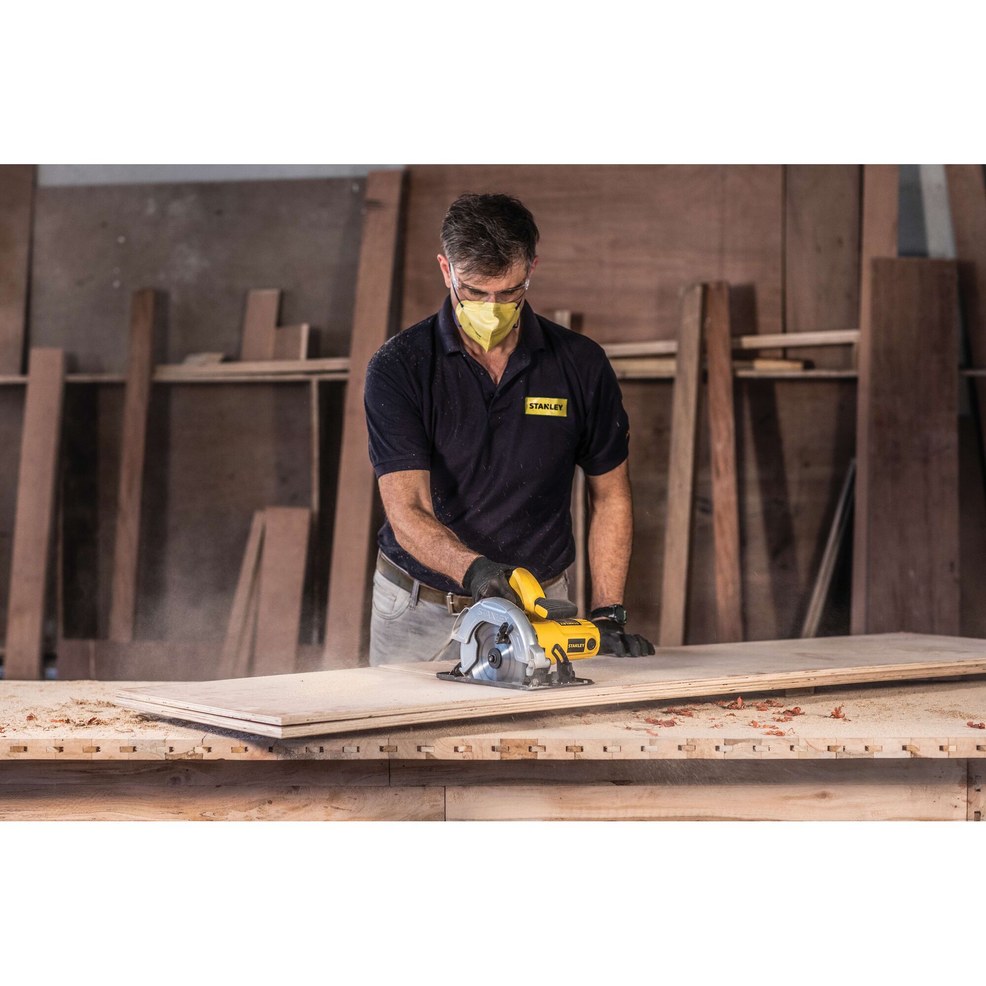 STANLEY SC16 circular saw in use cutting wood, worn by worker in workshop, product category photography.
