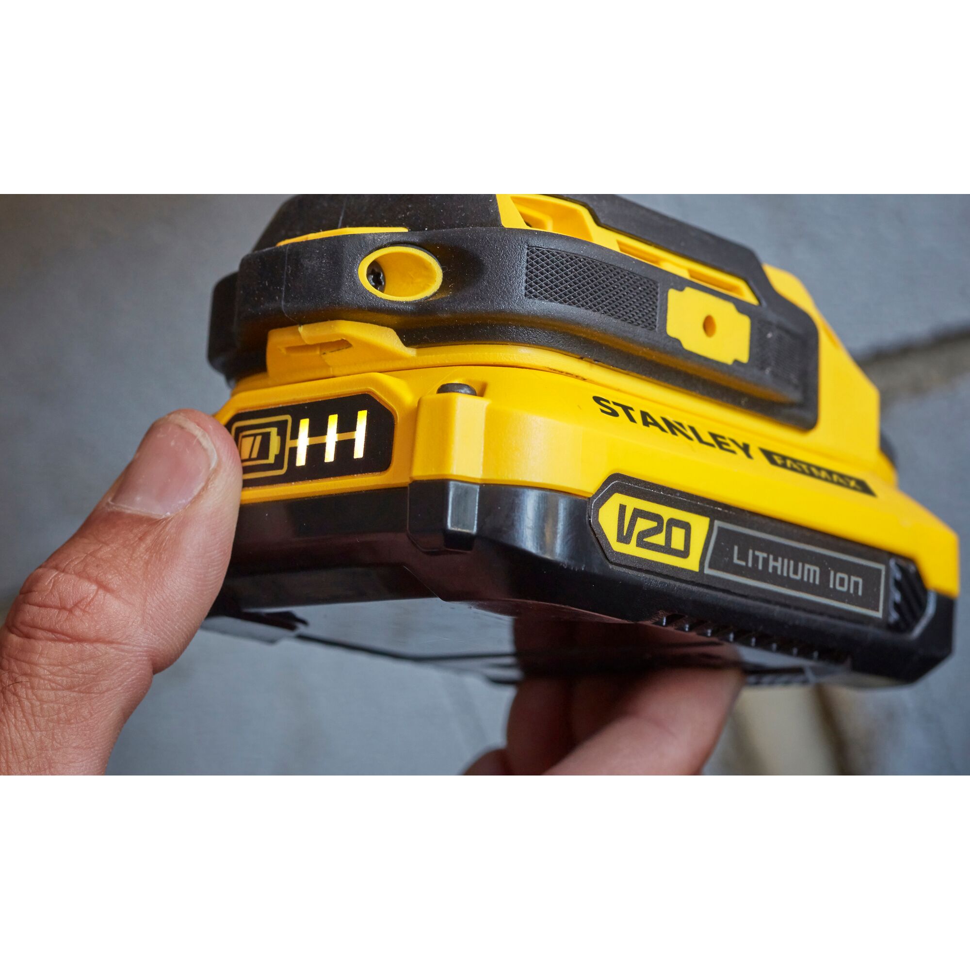 Stanley SCD711C1H-B2 V20 Lithium Ion battery held in hand, showing charge indicator and side branding.