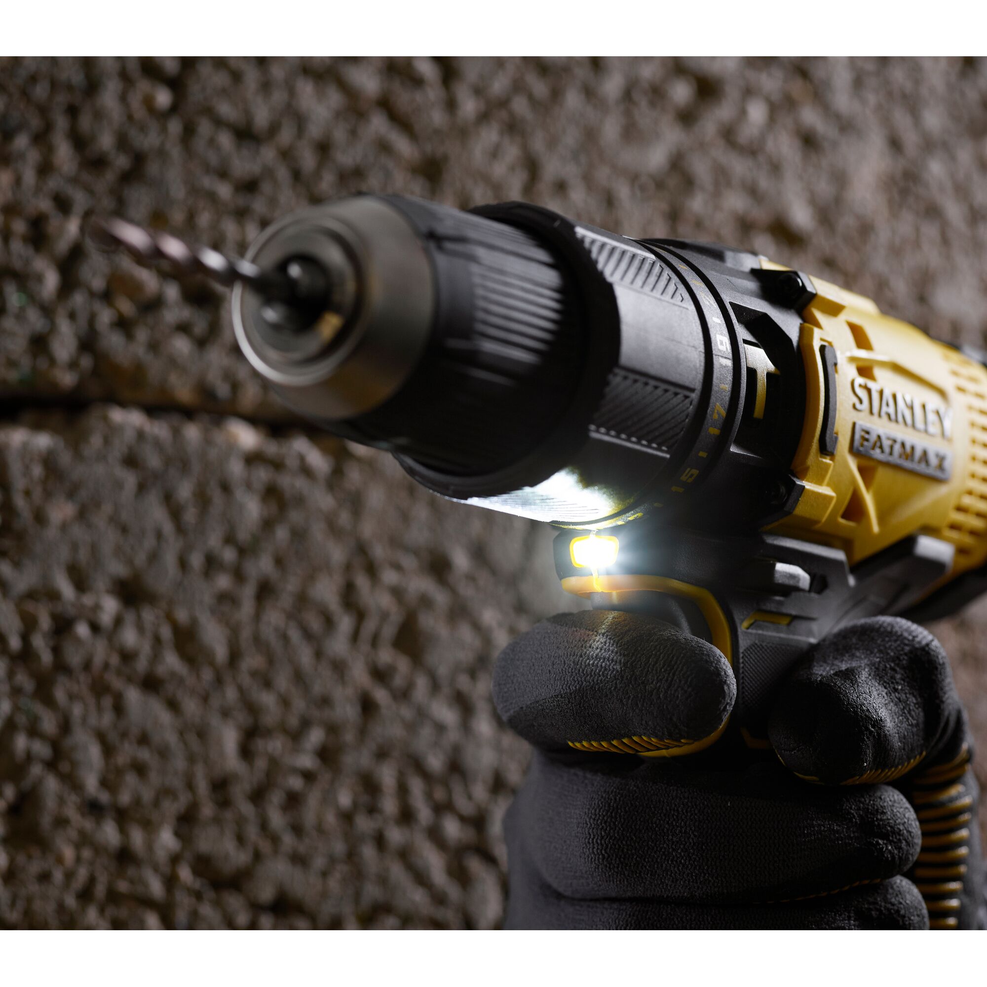 Stanley SCD711C1H-B2 cordless drill in use, close-up, yellow and black, with LED light on, photography.