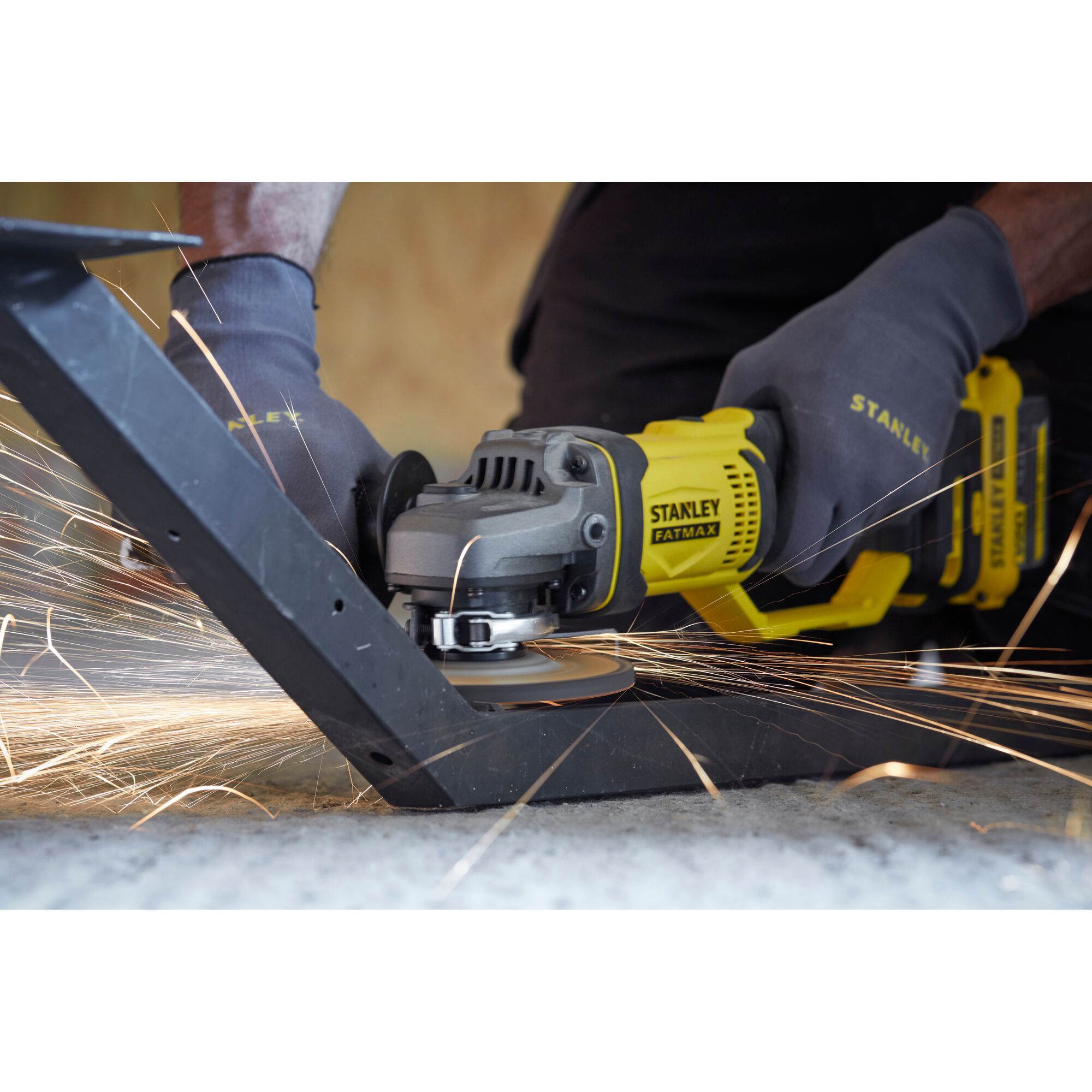 Stanley SCG400 angle grinder cutting metal with sparks, close-up photography of tool in use.