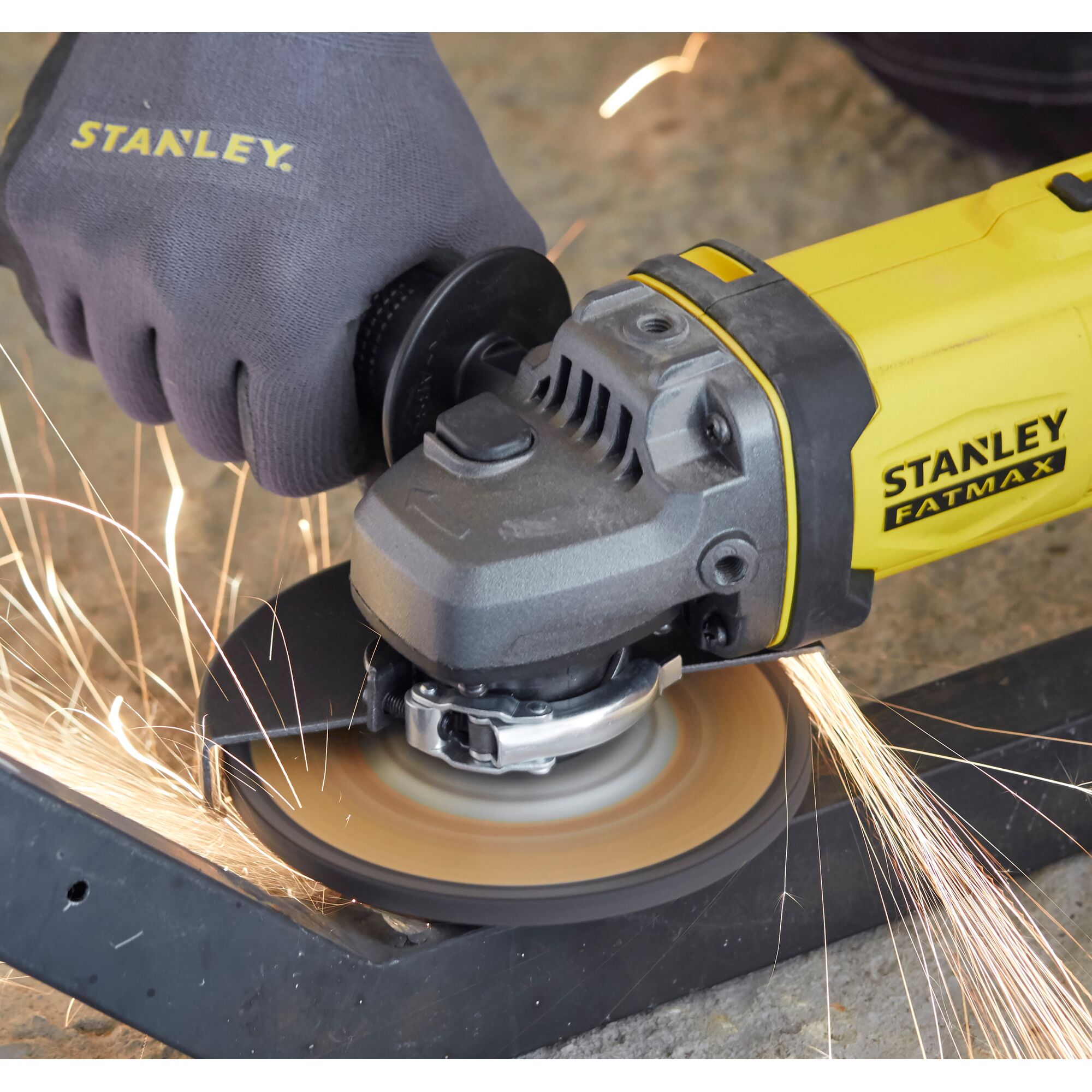 STANLEY SCG400 angle grinder cutting metal with safety glove, side angle photo.