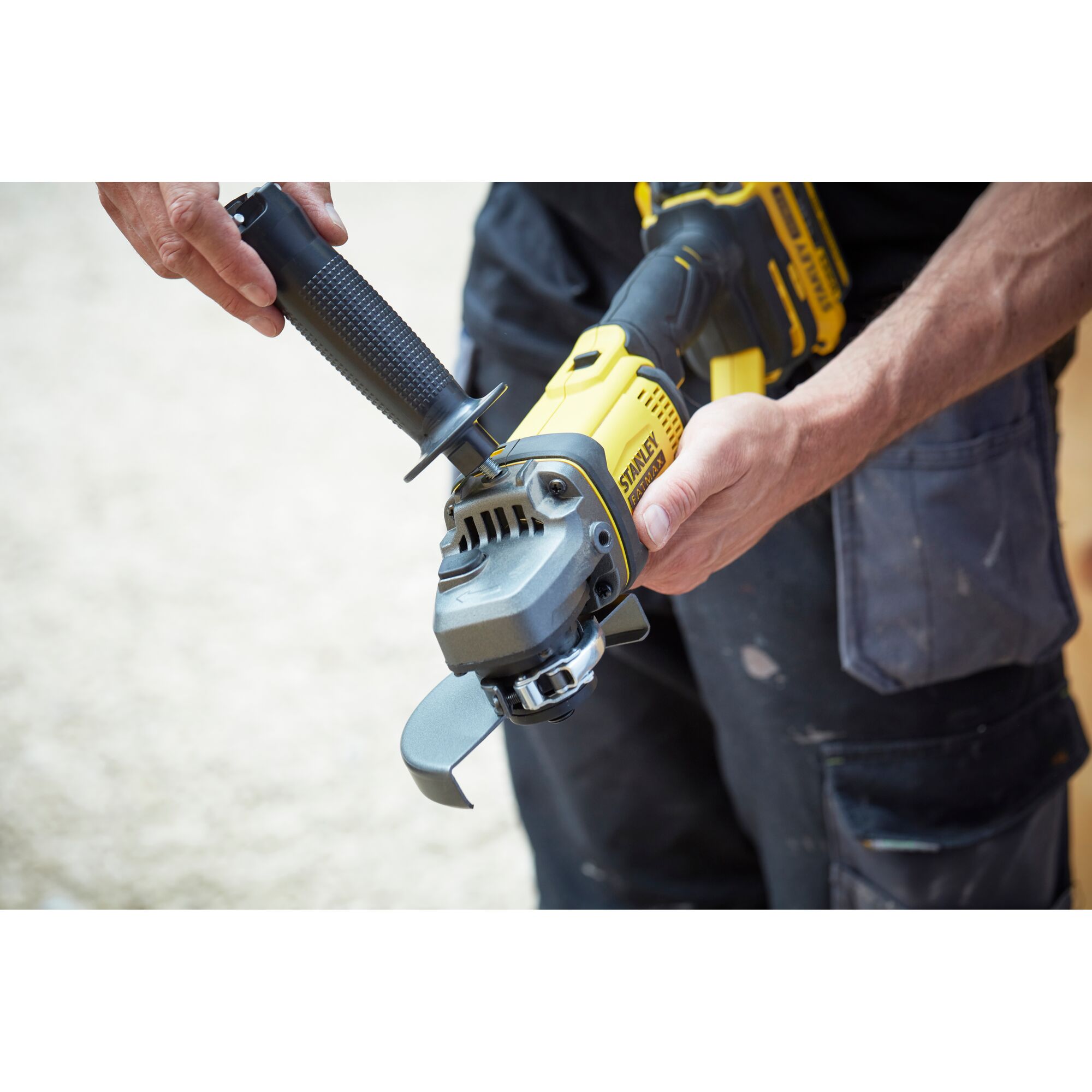 STANLEY SCG400 angle grinder held by a person, yellow and black design, close-up view.