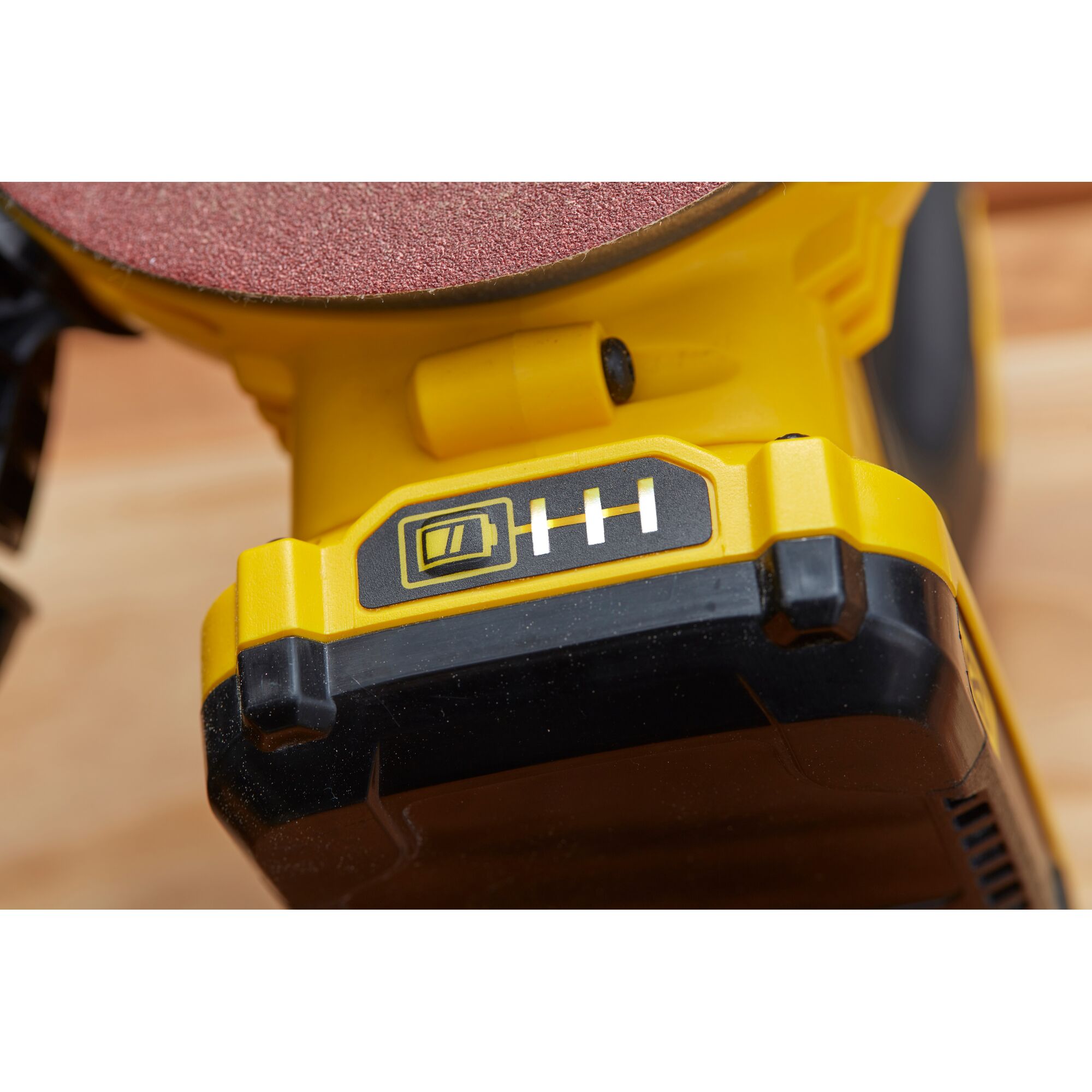 STANLEY SCS220 cordless sander battery close-up angle, yellow and black housing, partial sanding disc