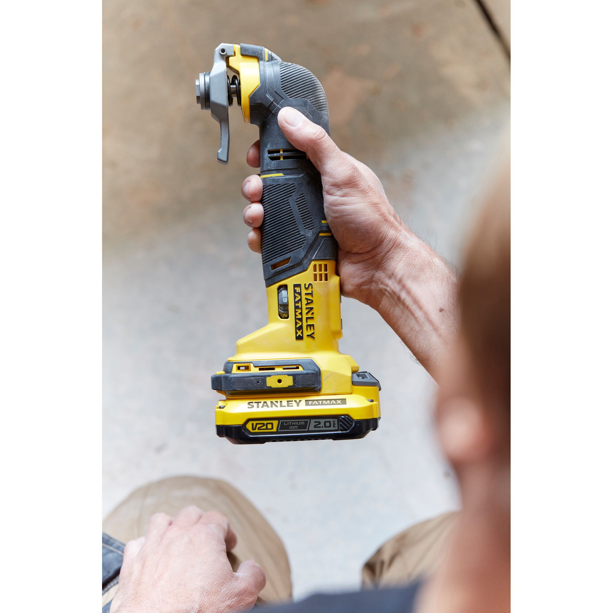 Stanley SCT500D2K oscillating multi-tool held by hand, yellow and black, side angle.