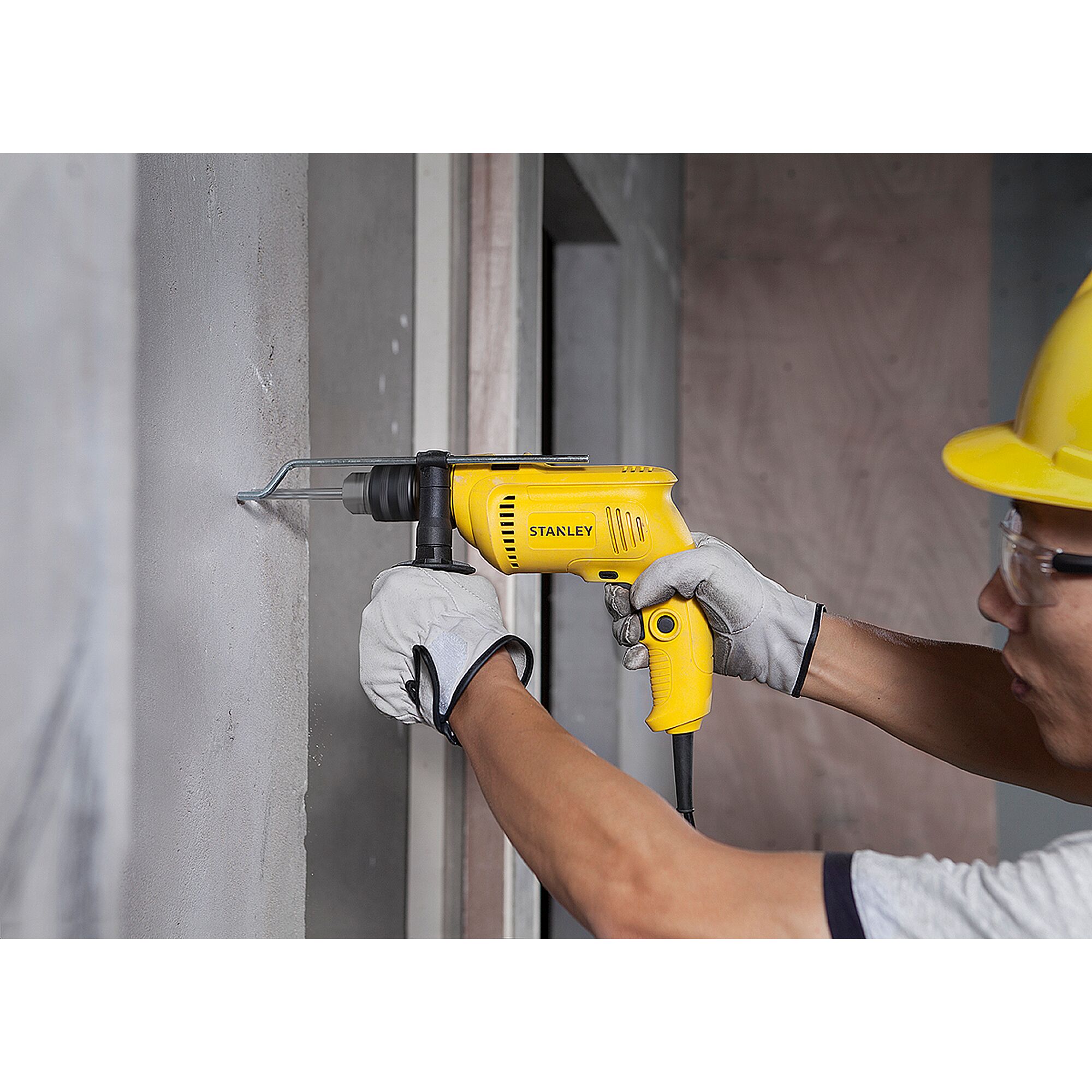 Stanley SDH600 yellow drill in use on concrete wall, close-up side angle, construction scene.
