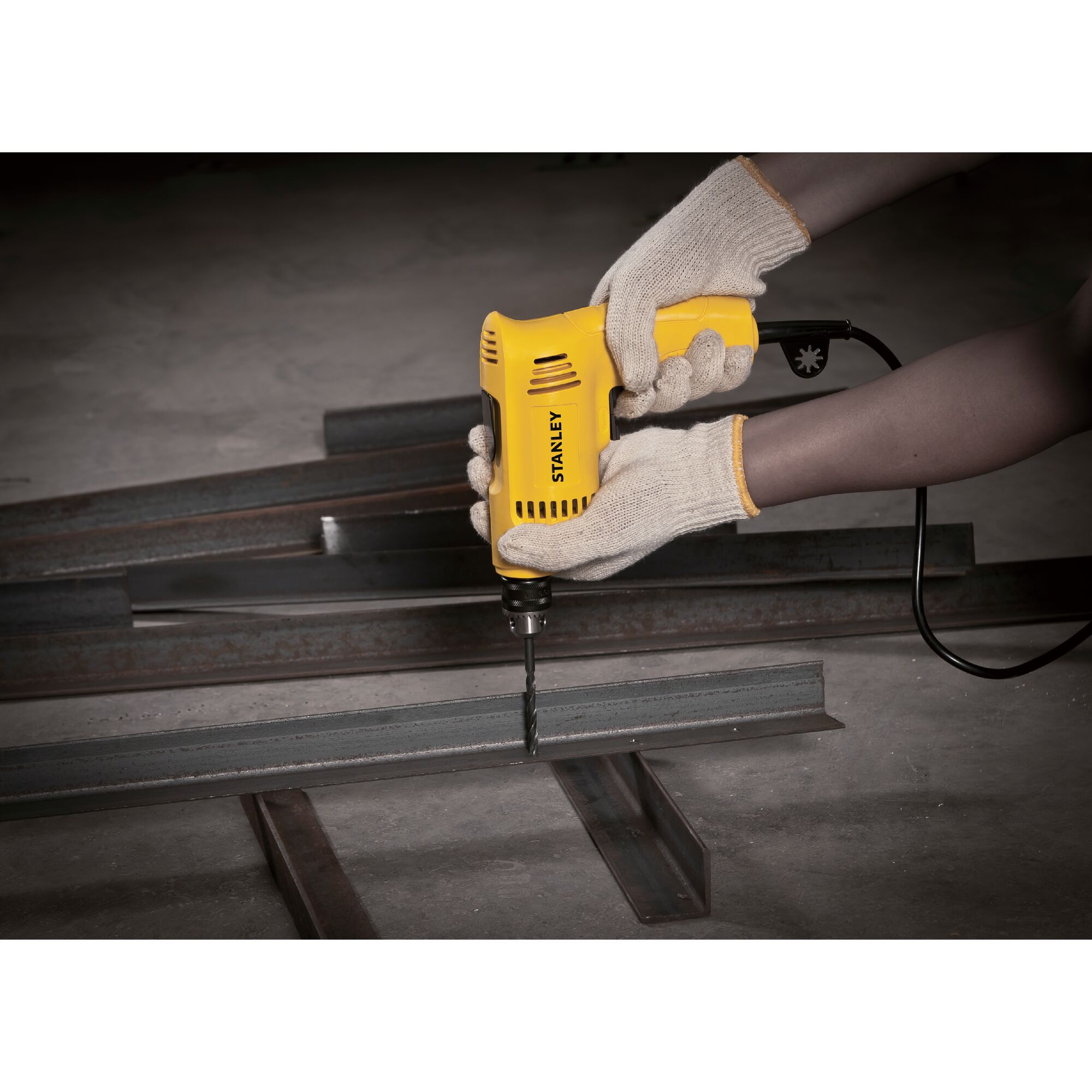 STANLEY SDR3006 electric drill being used on metal beams, worker wearing safety gloves.