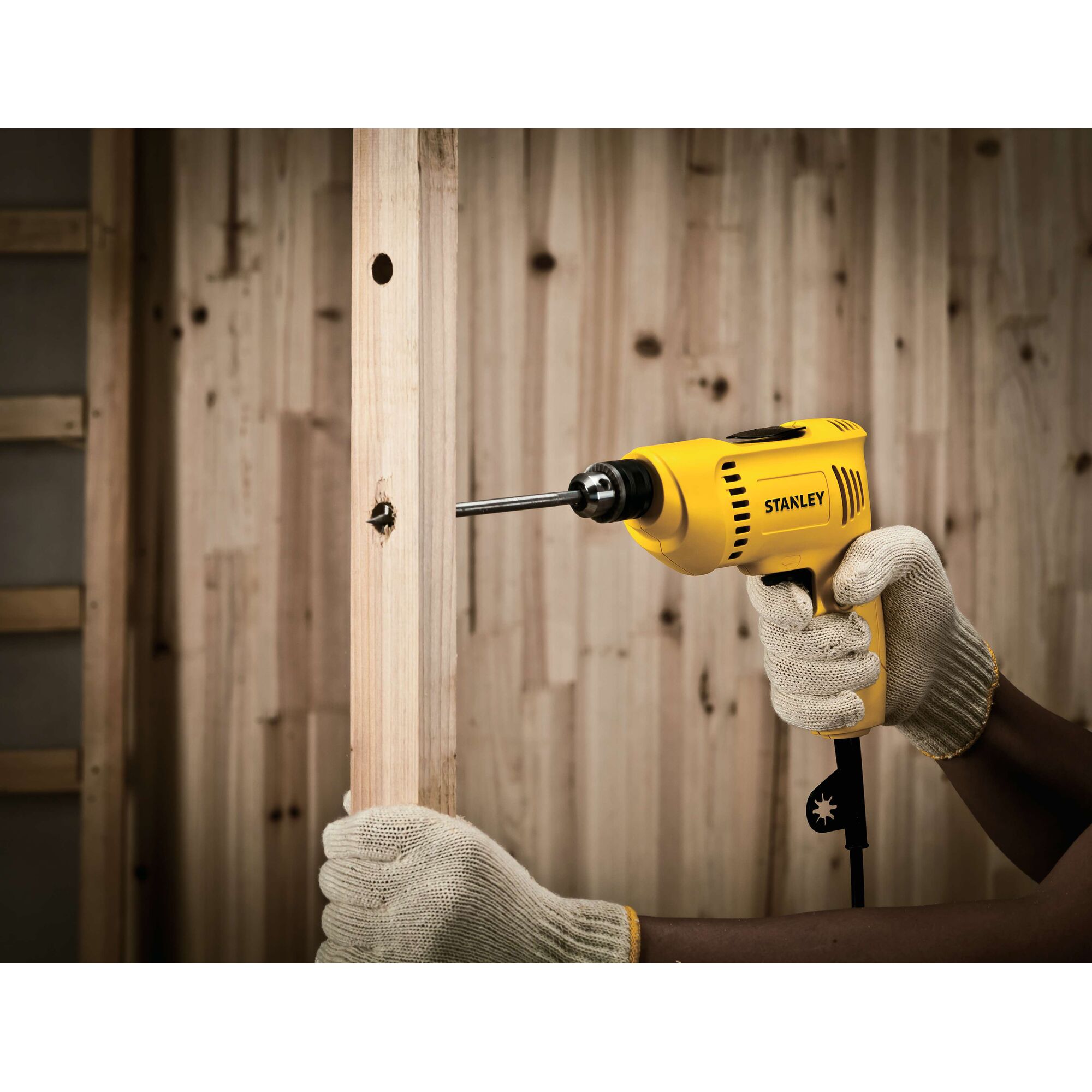 STANLEY SDR3006 electric drill in use drilling into a wooden beam, photography of power tool in action.