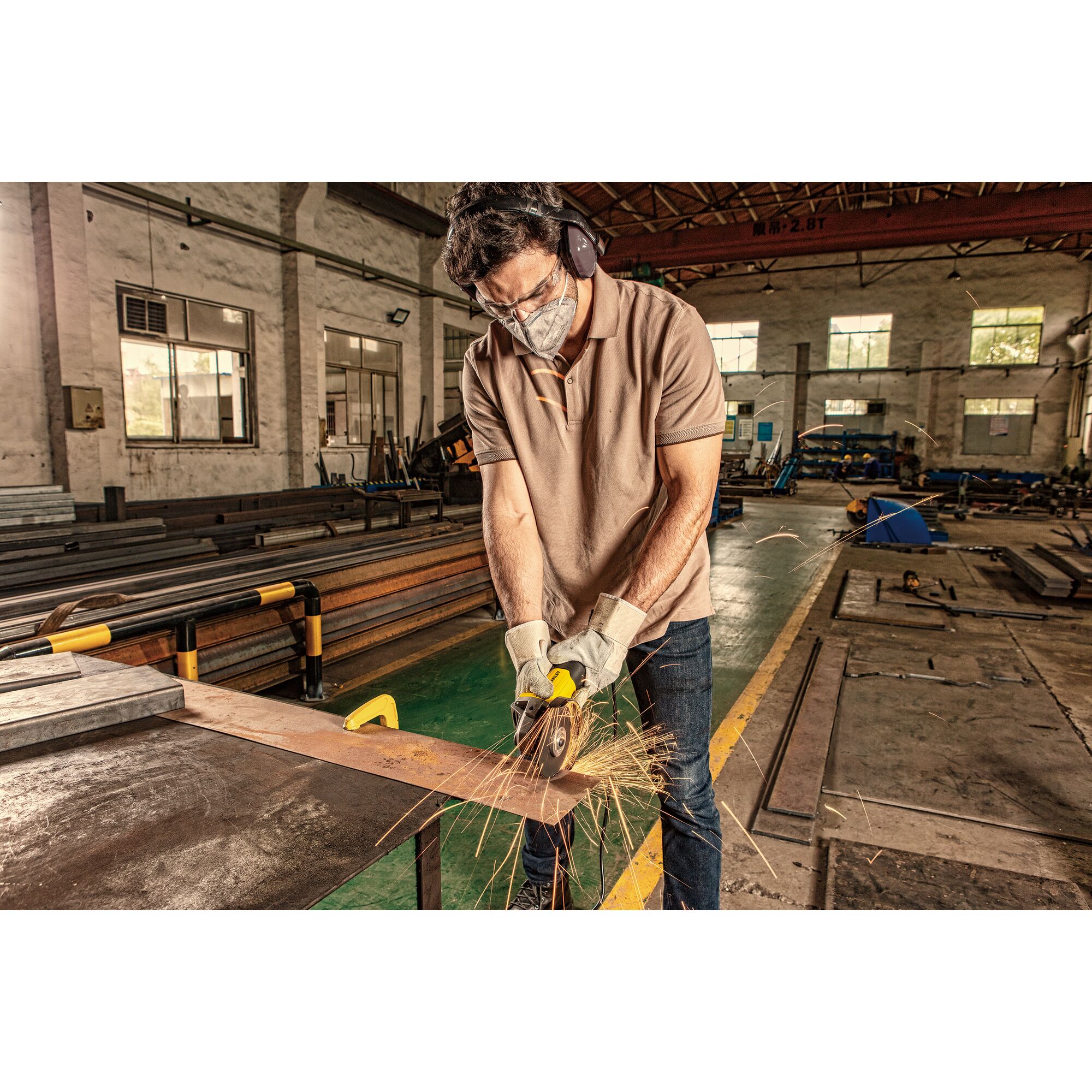 STANLEY SG7100 angle grinder in use at industrial workshop, sparks flying from metal cutting.