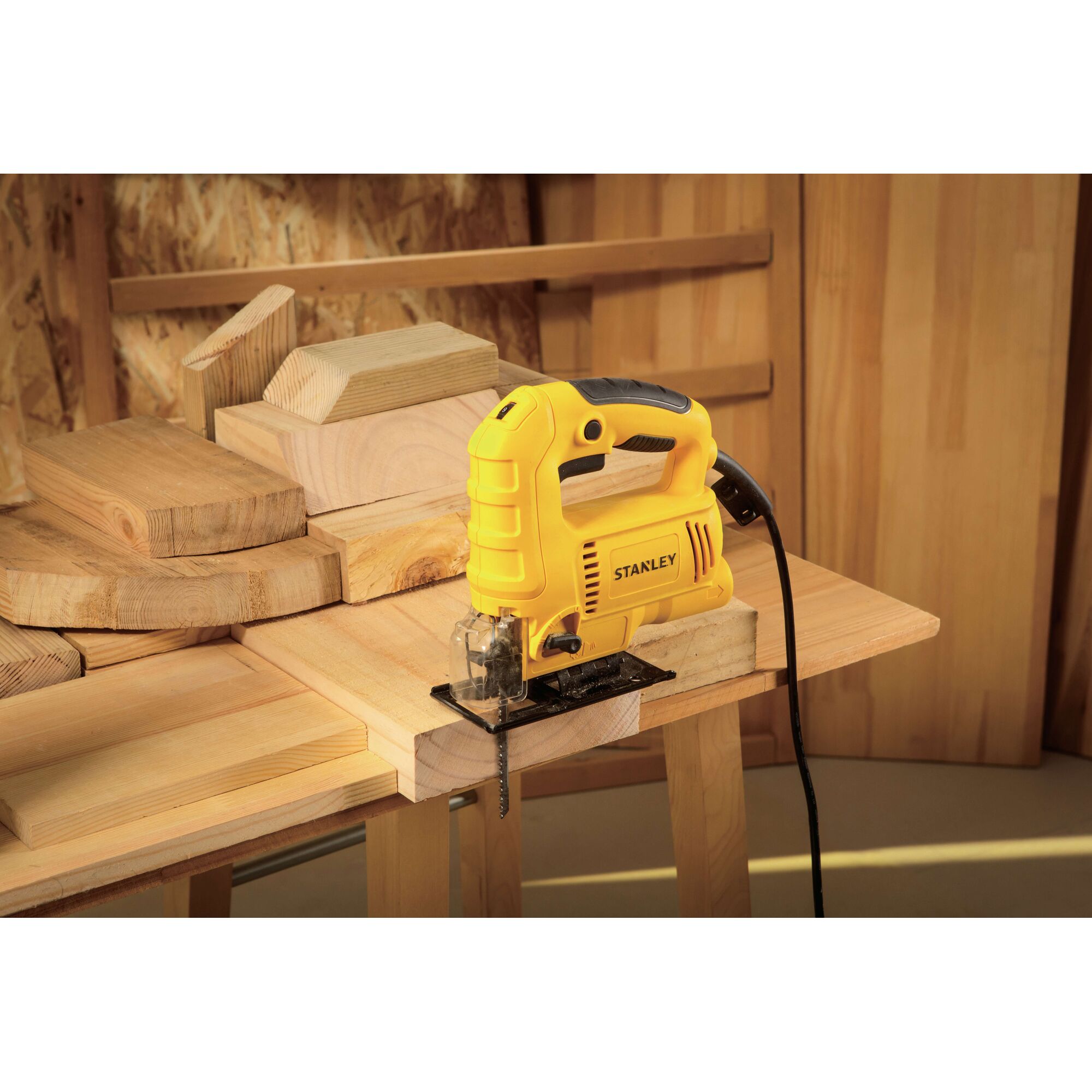 Stanley SJ60 jigsaw, yellow casing, shown on wood workspace with cut timber pieces, photography.