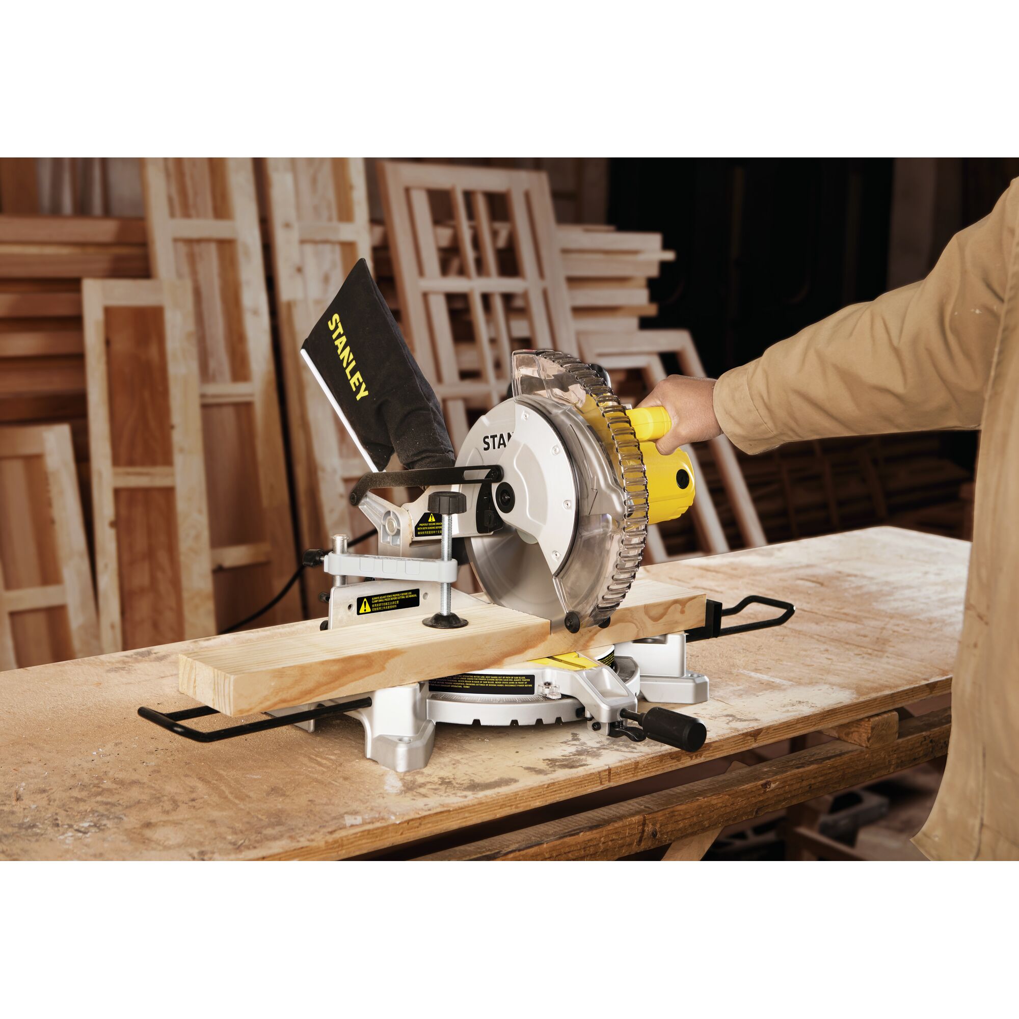STANLEY SM16-B3 miter saw in use, cutting wooden plank, workshop background, photography angle from side.