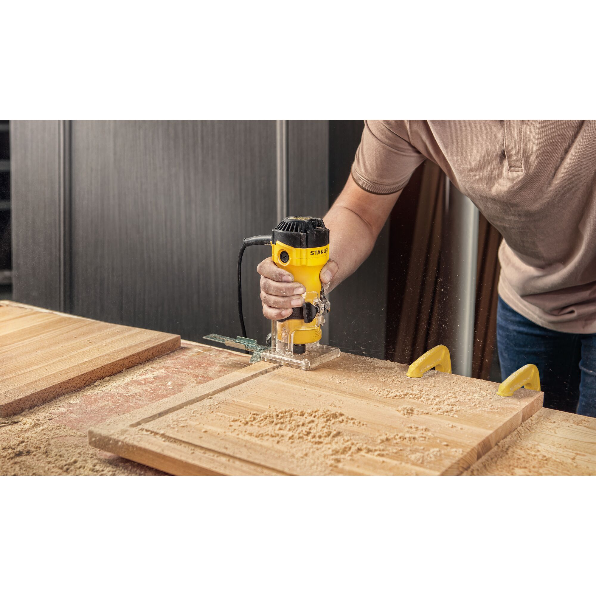 STANLEY ST55-B2 woodworking router used on a wooden board, yellow body, workshop setting.