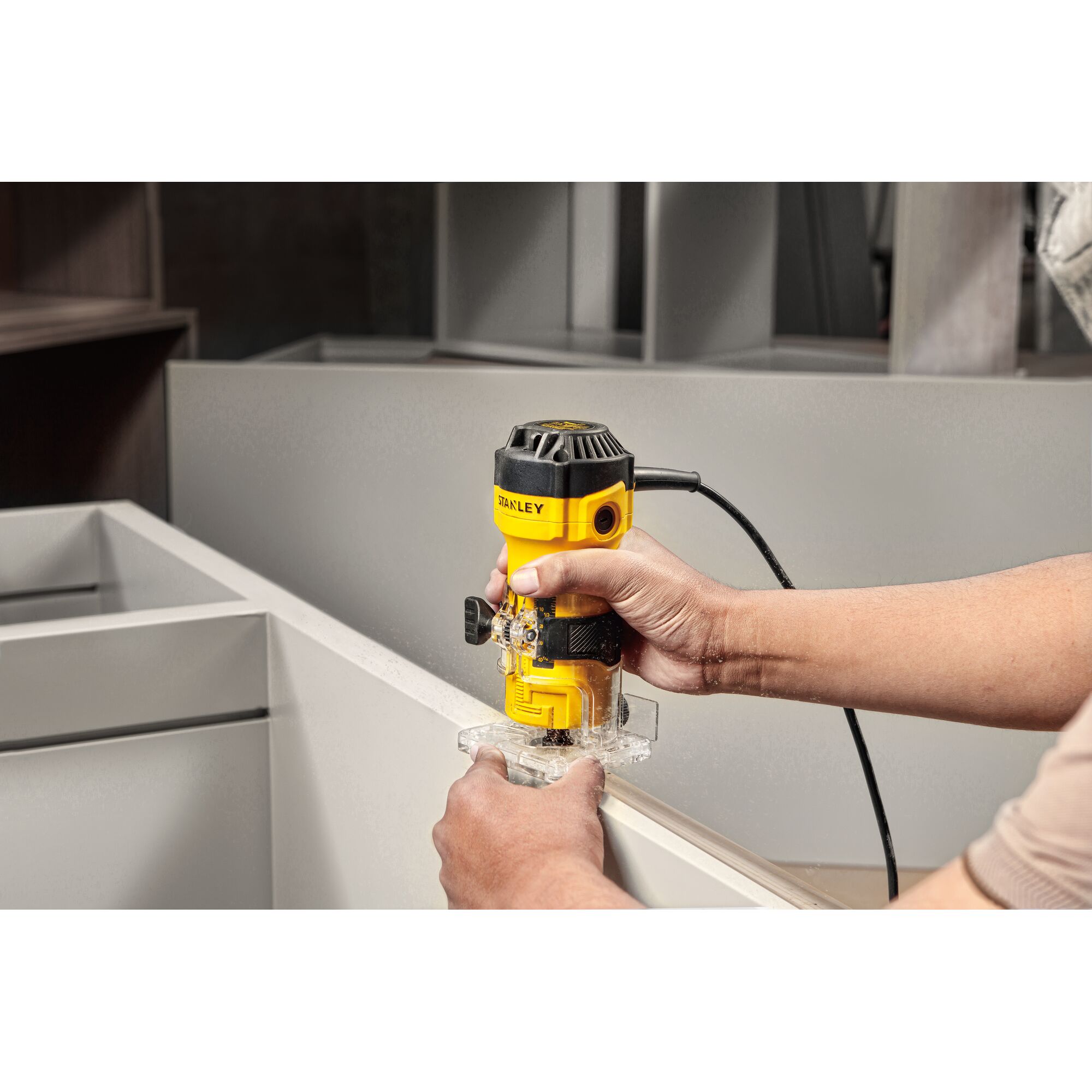 Photo of STANLEY ST55-B2 handheld electric trimmer being used on a cabinet edge, yellow and black color.