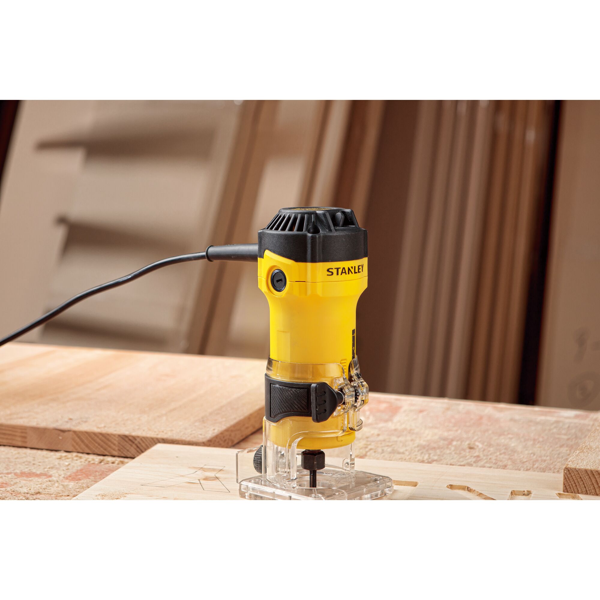 STANLEY ST55-KR compact yellow router on wood, corded, woodworking tool, side angle, workshop setting.