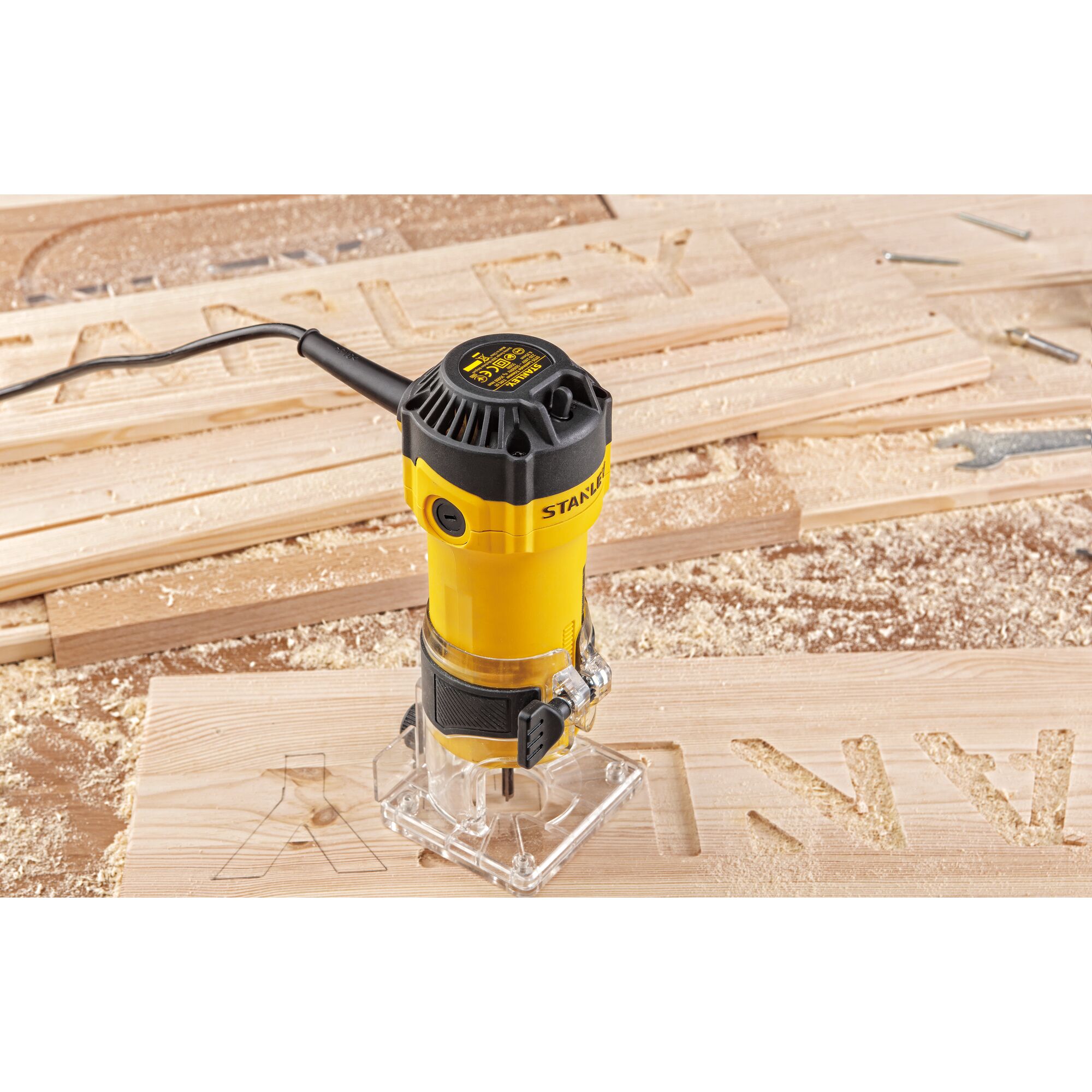 Stanley ST55-KR photography of yellow wood router on carved wooden board, showing tool in use.