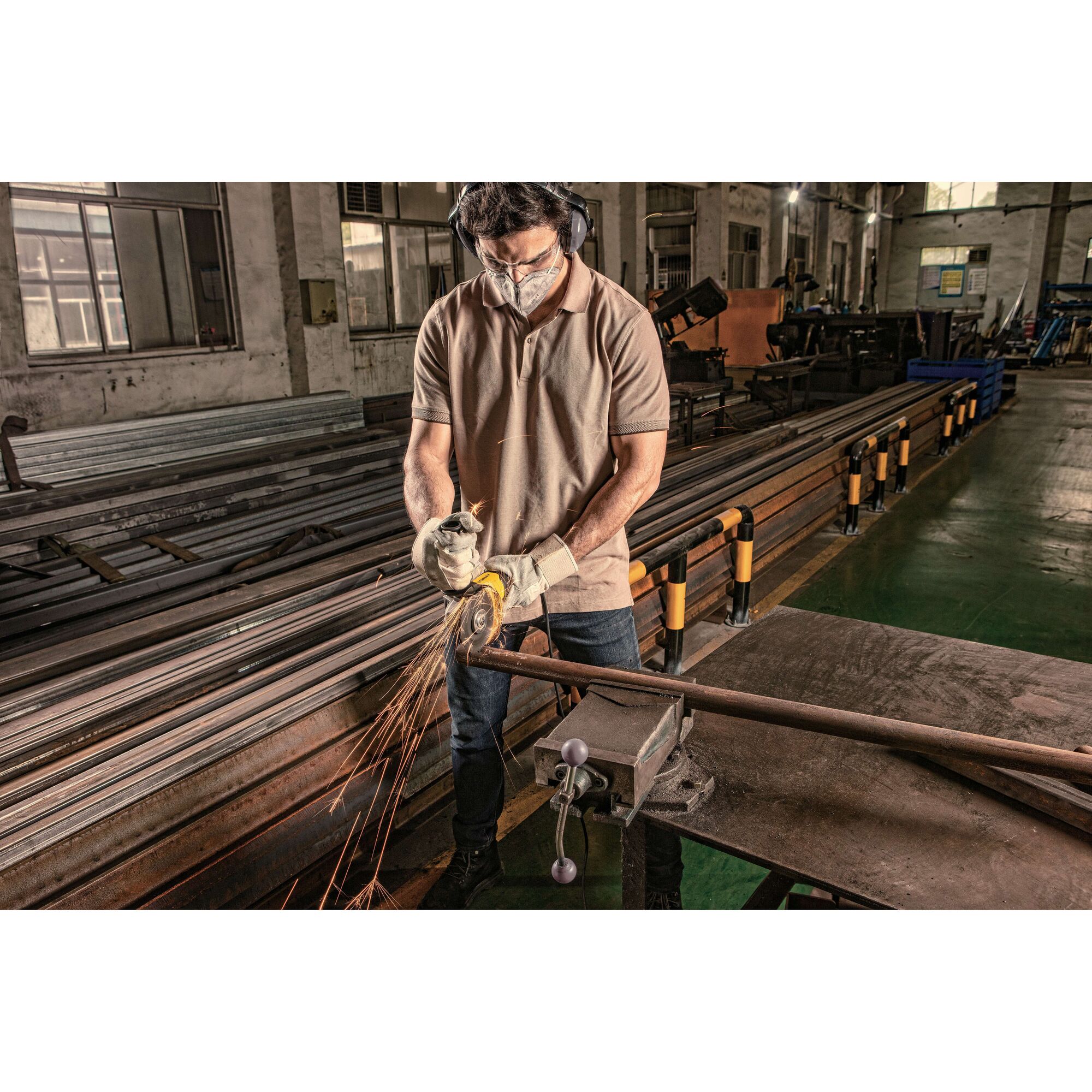 STANLEY STGS9100 grinder in use with protective gloves cutting metal pipe in industrial workshop.