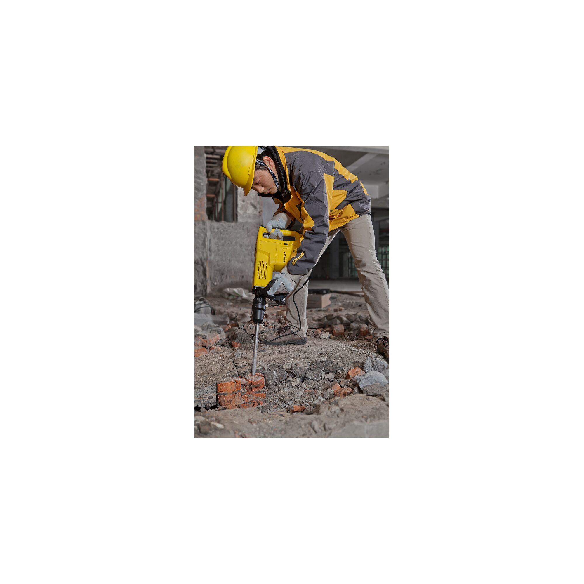 Stanley STHM10K demolition hammer shown in use breaking concrete rubble at a construction site.