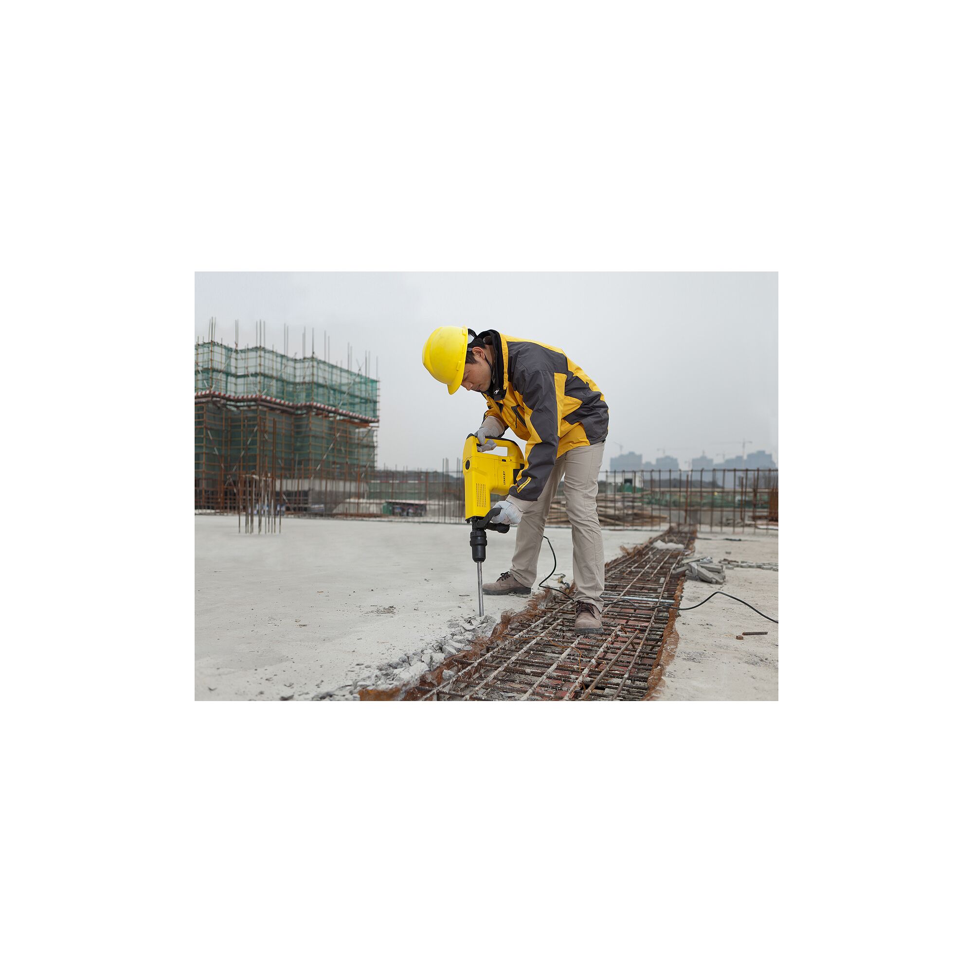 STANLEY STHM10K demolition hammer in use at a construction site, worker breaking concrete.